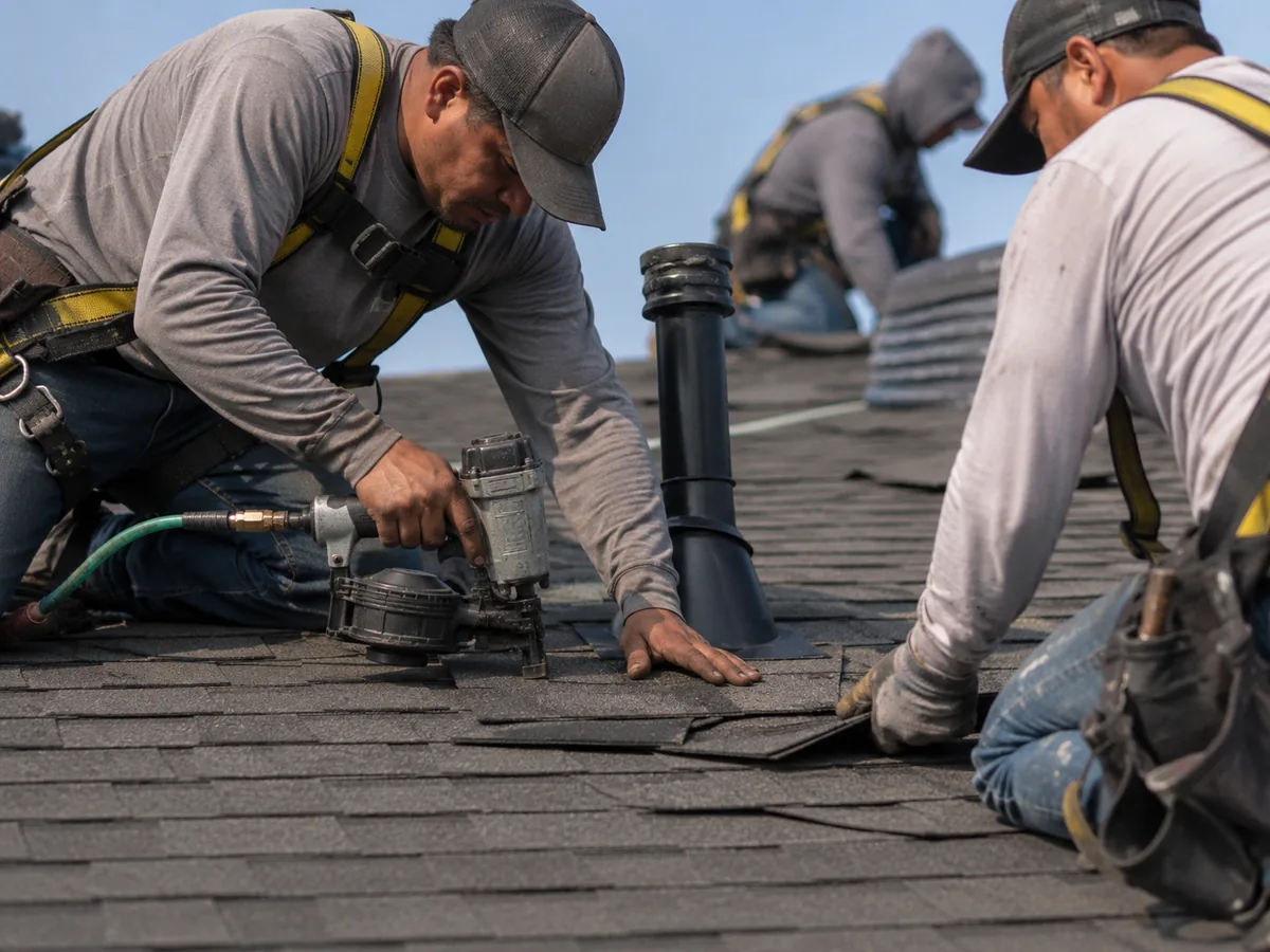 Roofing contractors installing asphalt shingles on a residential roof