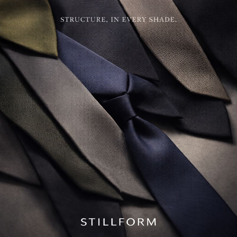 Artistic overhead shot of multiple Stillform ties in different fabric textures and shades